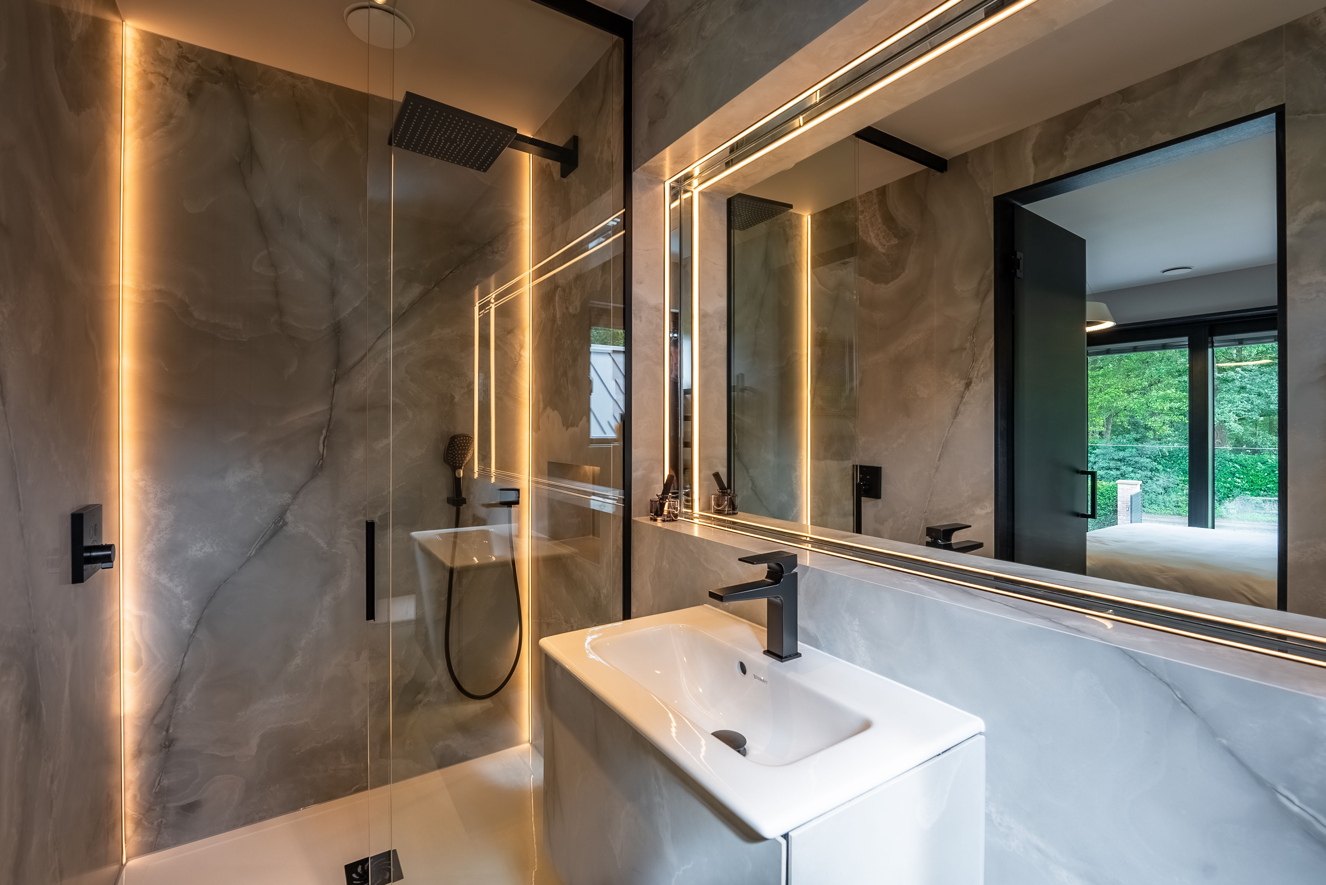 Backlit bathroom mirror with dark marble surround