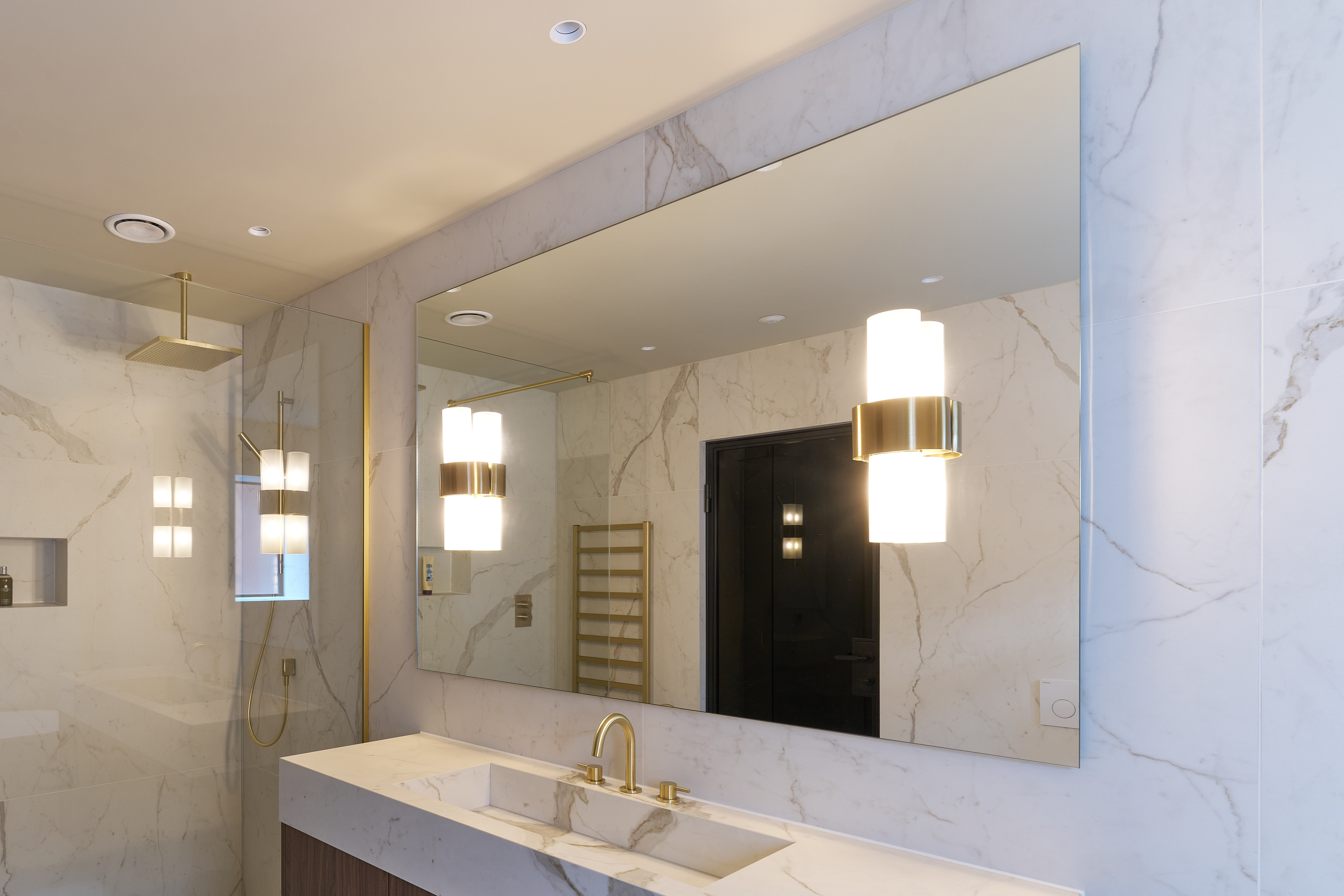 Large frameless mirror in marble bathroom