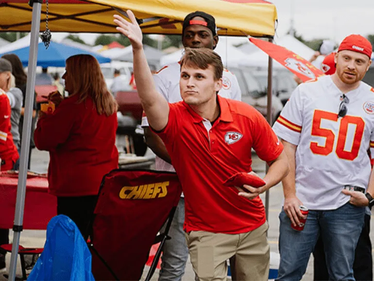 KC Current players in red jerseys celebrating a thrilling goal on game day, with fans cheering in the background. Make every match memorable with KC Current Game Day Transportation for hassle-free stadium access.