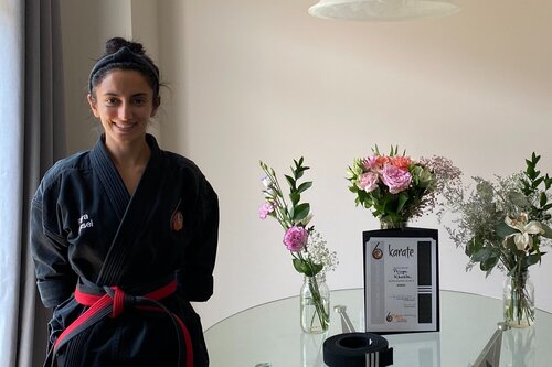Priya sensei standing in the ottawa dojo beside a table with a flower arangement 