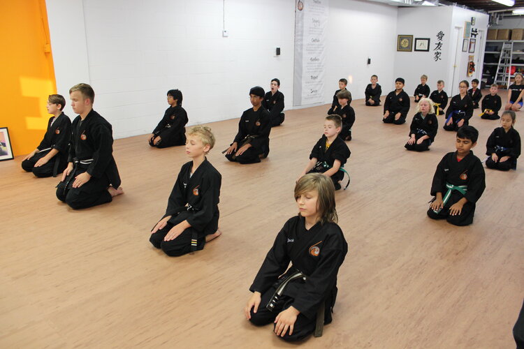 A class of children's karate students kneeling and breathing as part of the cirriculum