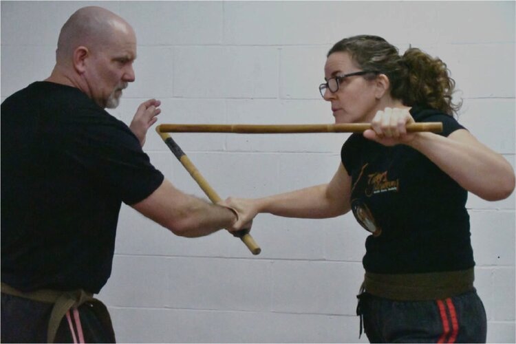 2 senseis sparring with kali sticks in the dojo