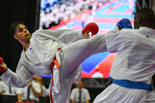 6tigers student competing in an international karate tournament, kicking their opponent in a sparring match