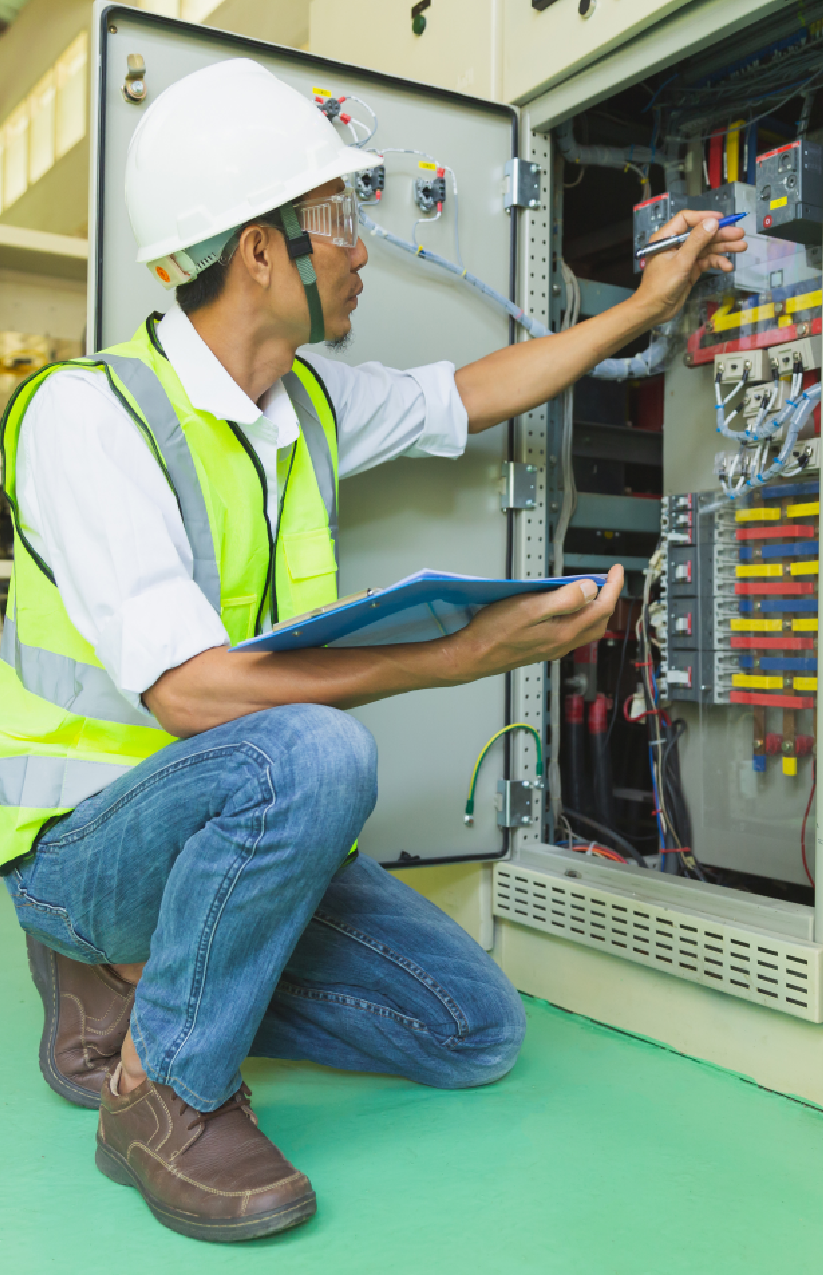 ETS technician performing diagnostics on an industrial generator control cabinet with tablet and safety gear