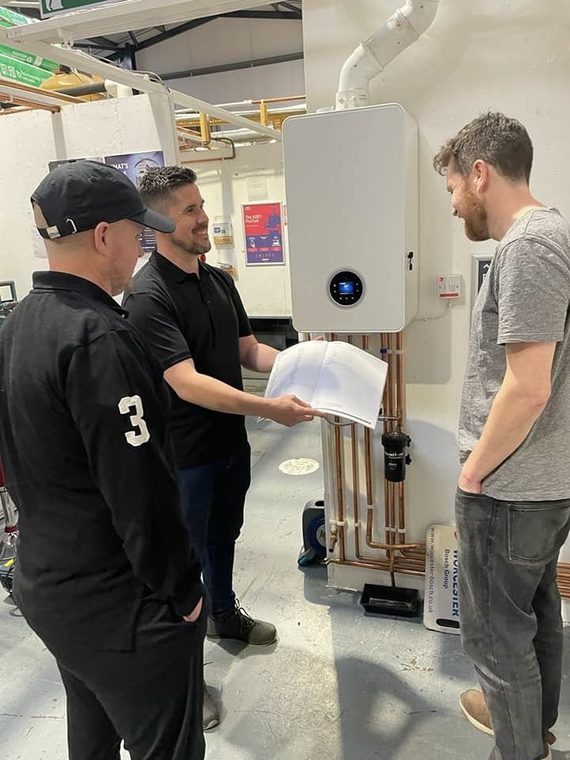 Rob Davis going through a manual with two heating installers at a training centre