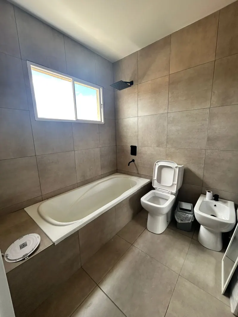Baño con porcelanato de gran formato, bañera empotrada y ventana alta.