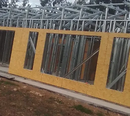 Estructura de perfiles metálicos con cabriadas en la cubierta y muros revestidos con placas de madera.