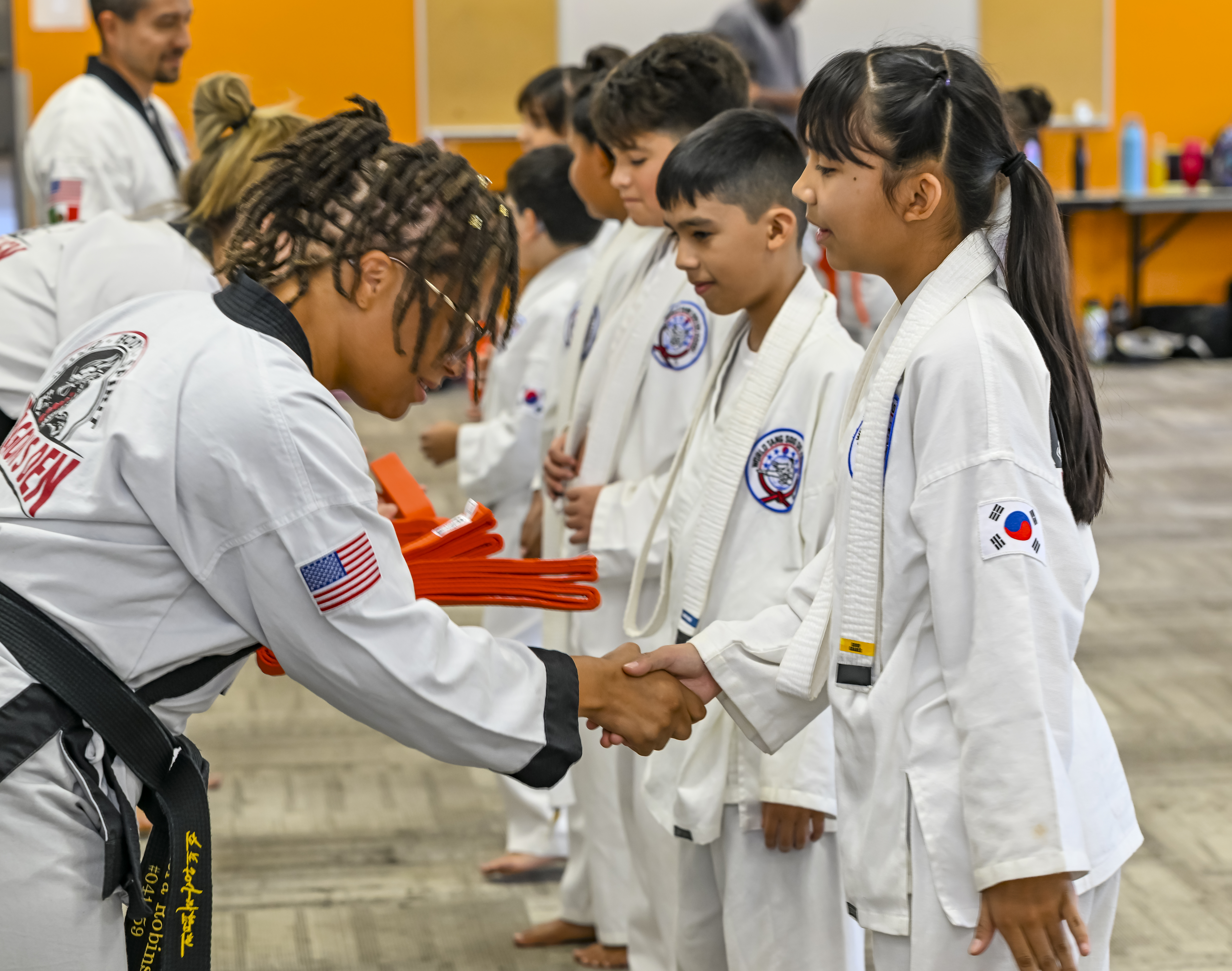 A black-belt instructor correcting a student's stance