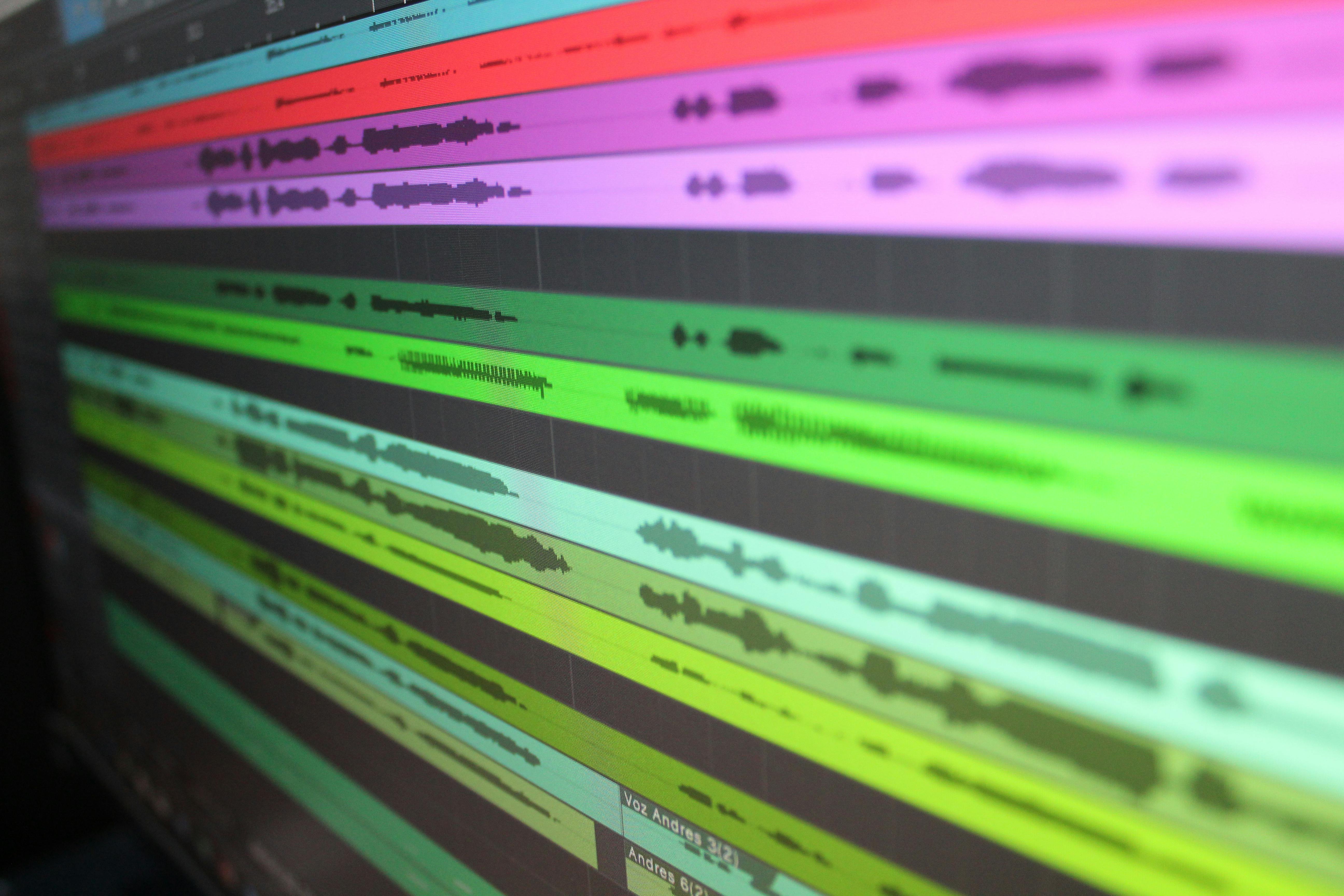 Close-up of colourful audio tracks in a digital audio workstation, illustrating layered music production and parallel processing in a mix.