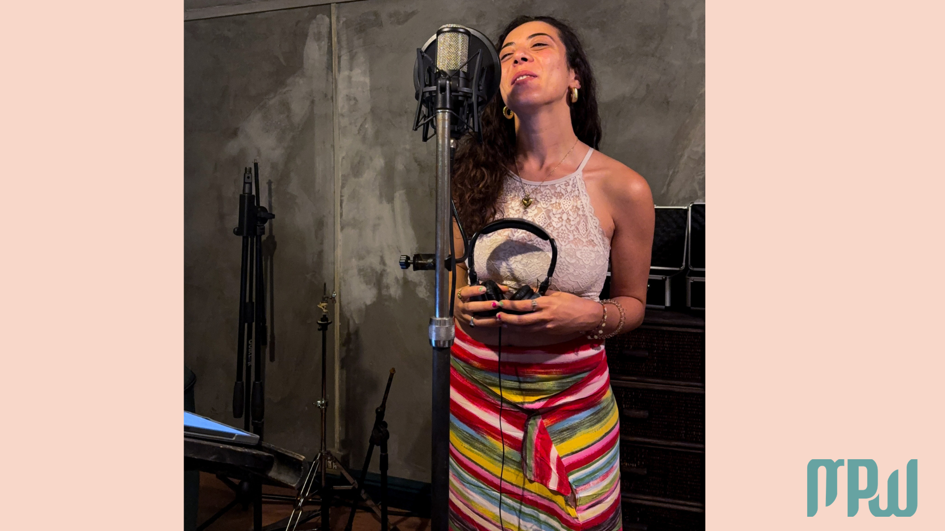 Reiwa Pia singer recording vocals in a home studio with a condenser microphone, headphones, and warm lighting