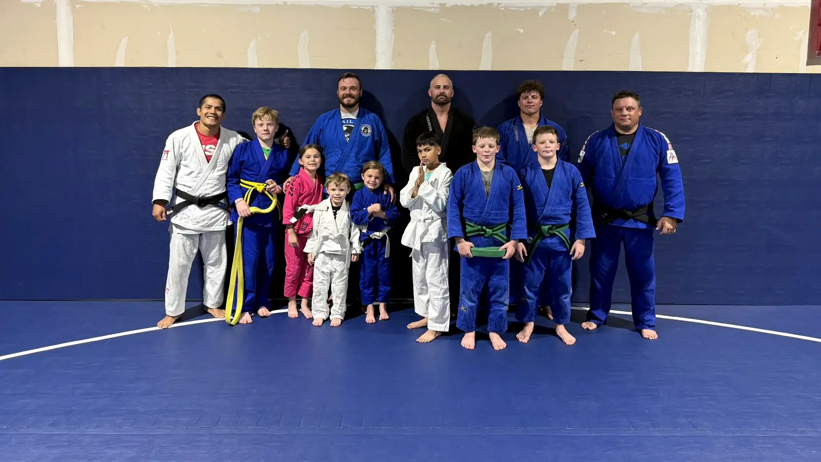 Dominion Academy judo students and coaches smiling together on the mat