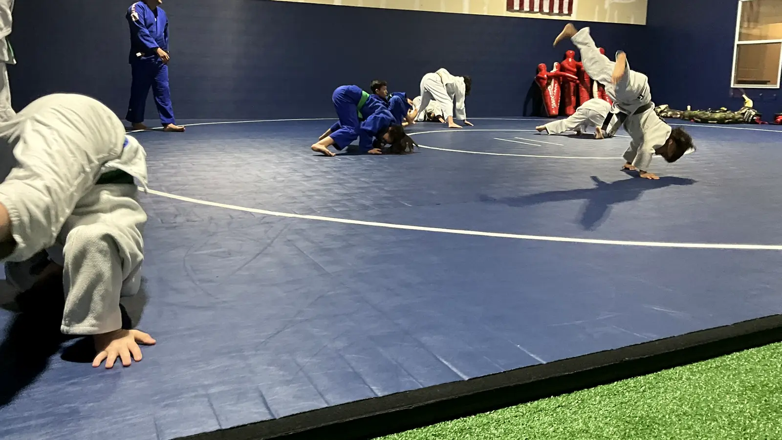 Several pairs practicing judo throws during an evening class