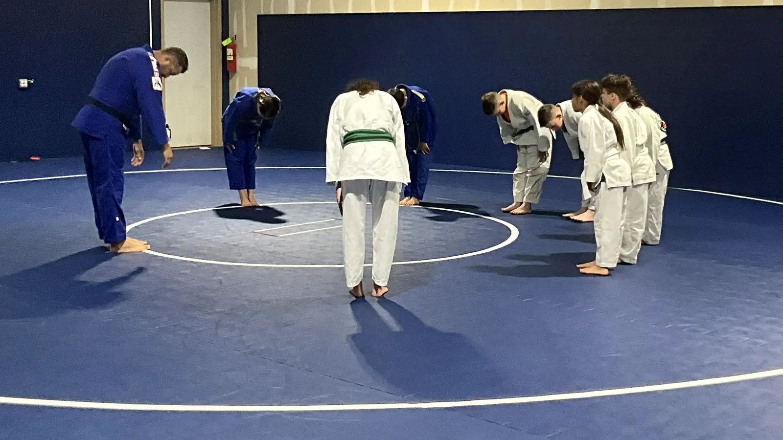 Judo coach and students bow to each other at the start of class