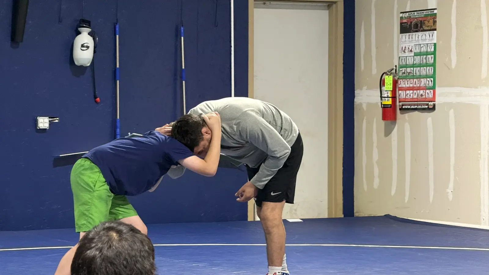 Wrestling coach demonstrating a collar tie with a young wrestler