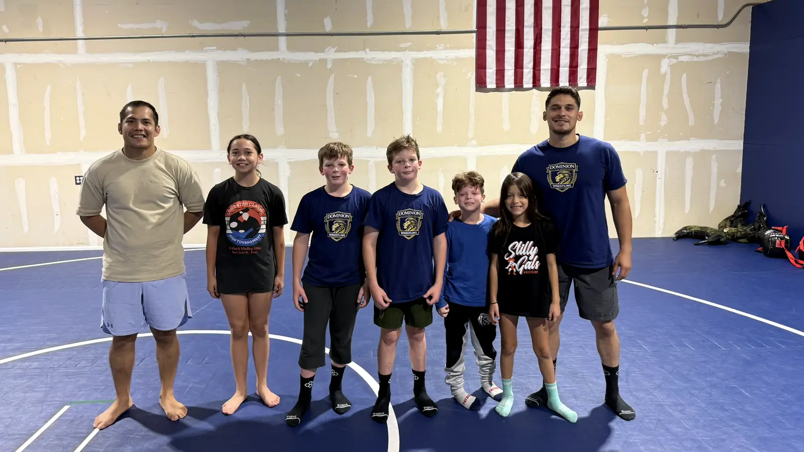 Young wrestlers and their coaches smiling together under the American flag