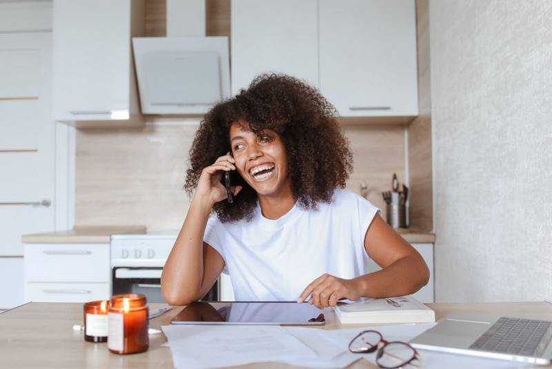 Woman talking on the phone at a kitchen table (stock photo)