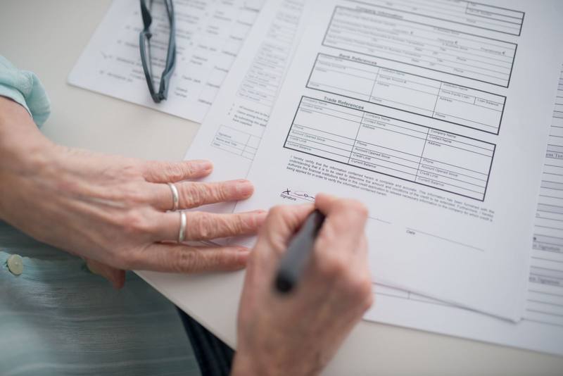 Hand signing a printed form (stock photo)