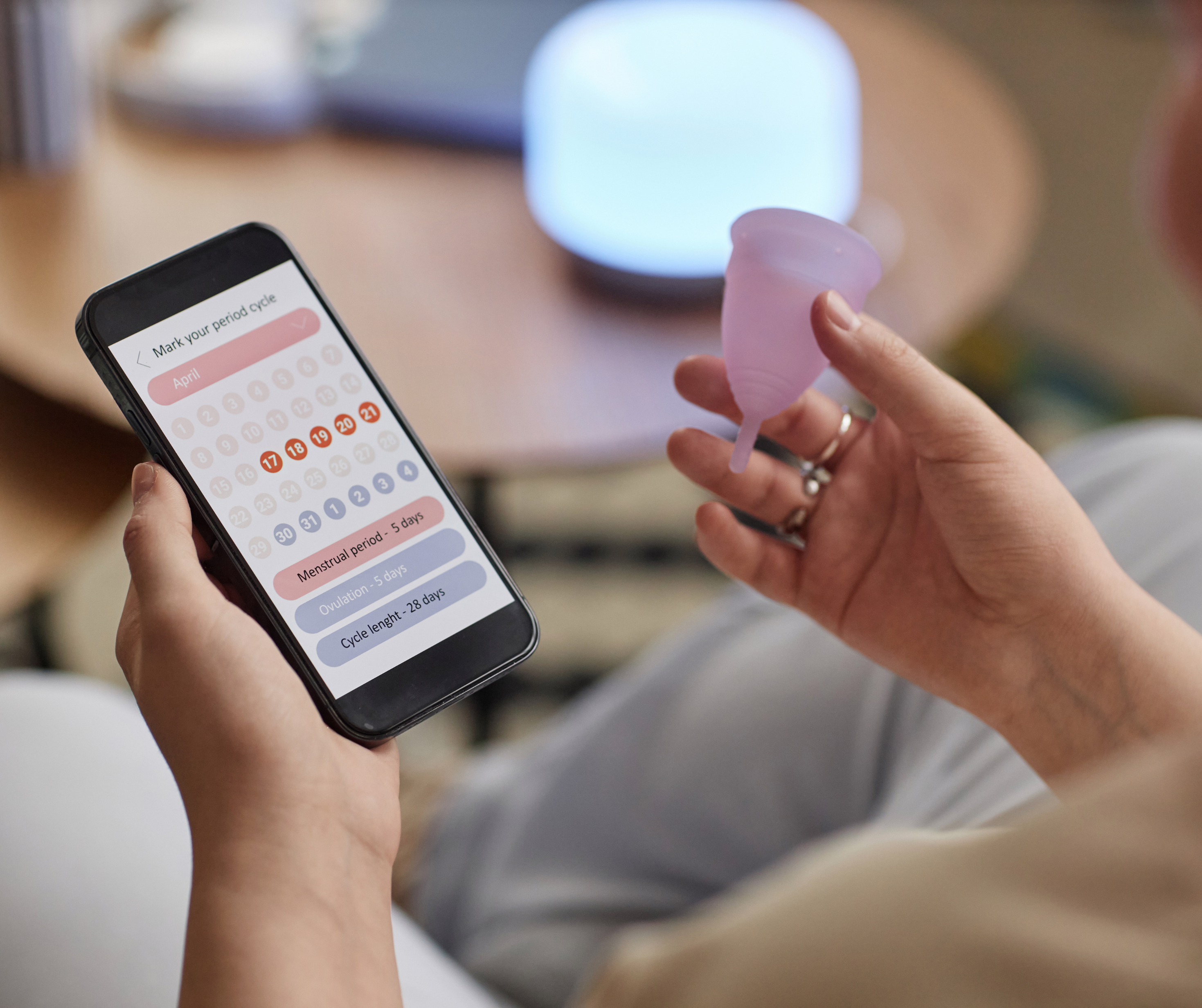 Cycle tracking on a phone beside a menstrual cup