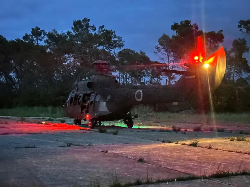 Military transport helicopter on a ramp at dusk with its red beacon lit