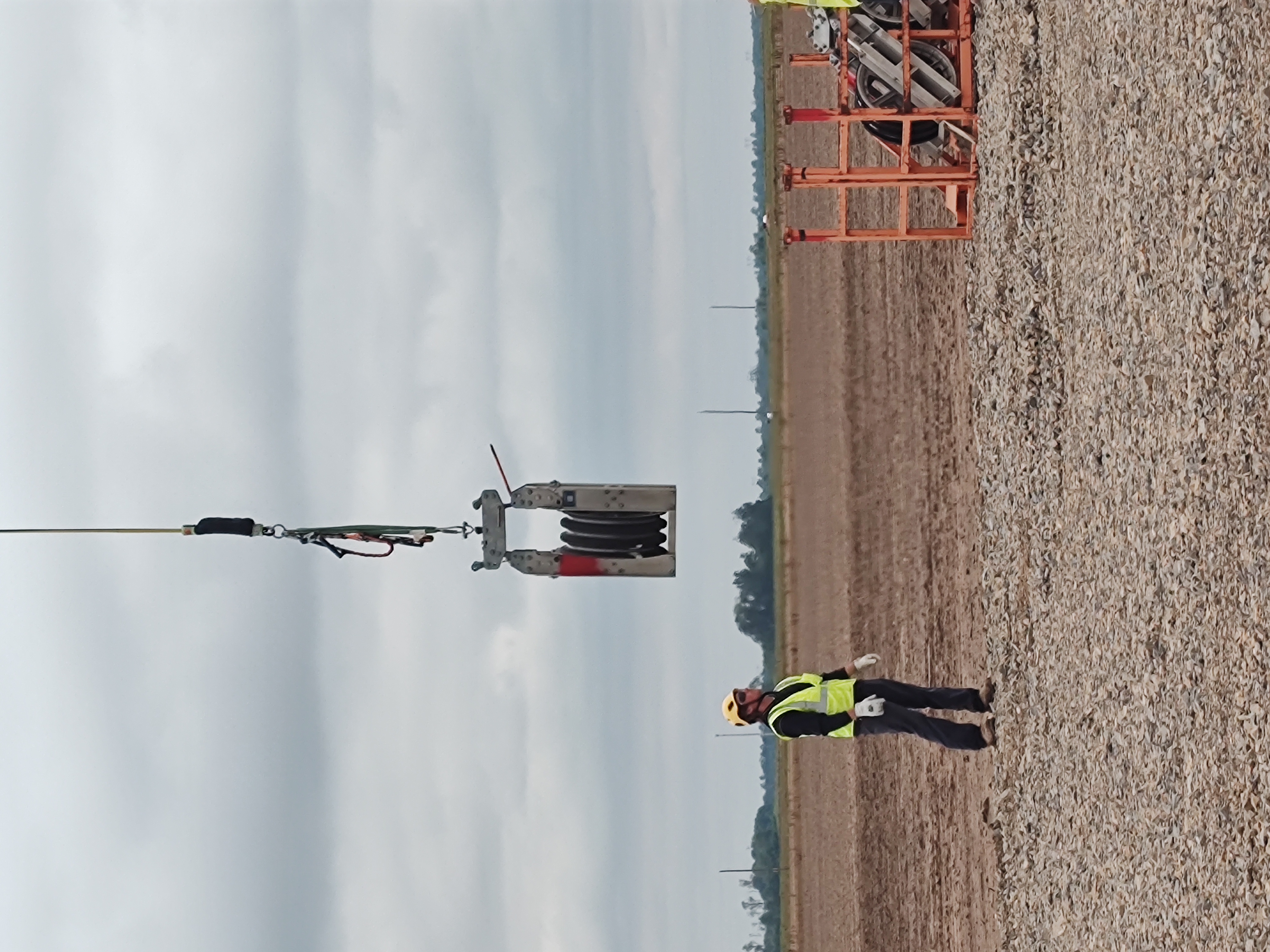 Construction crew member guiding external load rigging during helicopter lift