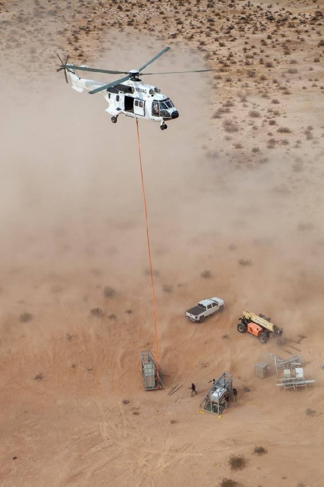Helicopter transporting external load equipment to remote construction site