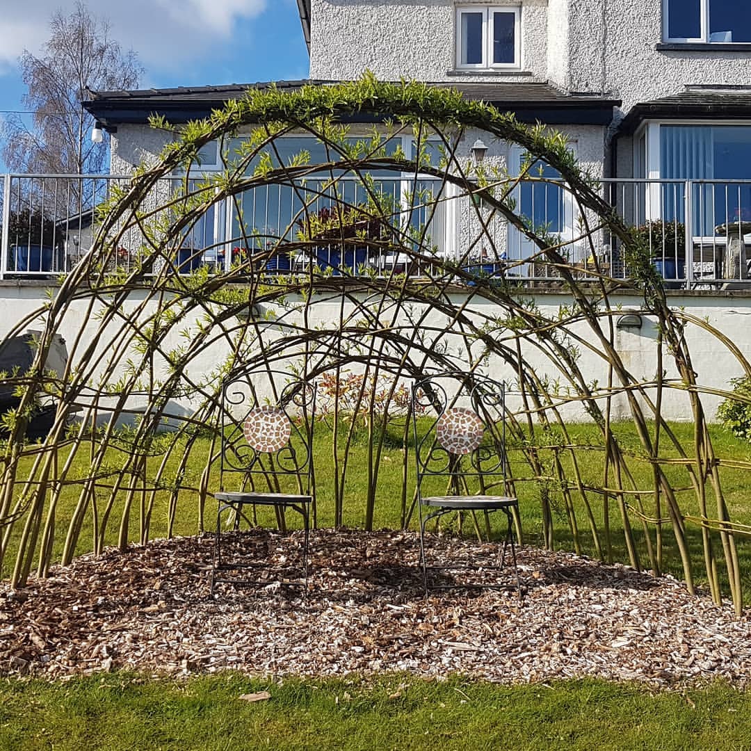 Two chairs under an archway made of woven branches of wood