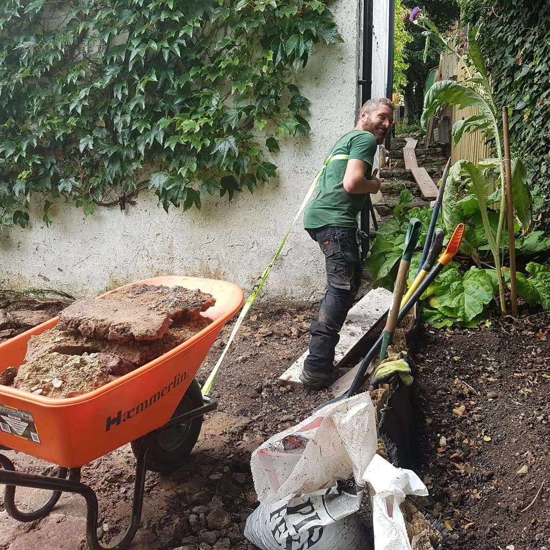 Matthew pulling a wheelbarrow full of rock tiles up improvised stairs