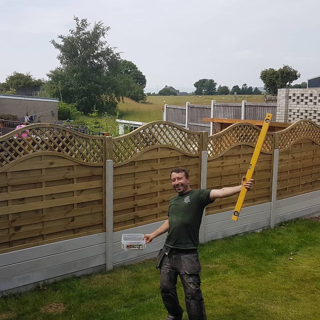 Happy friend proudly standing in front of finished fence