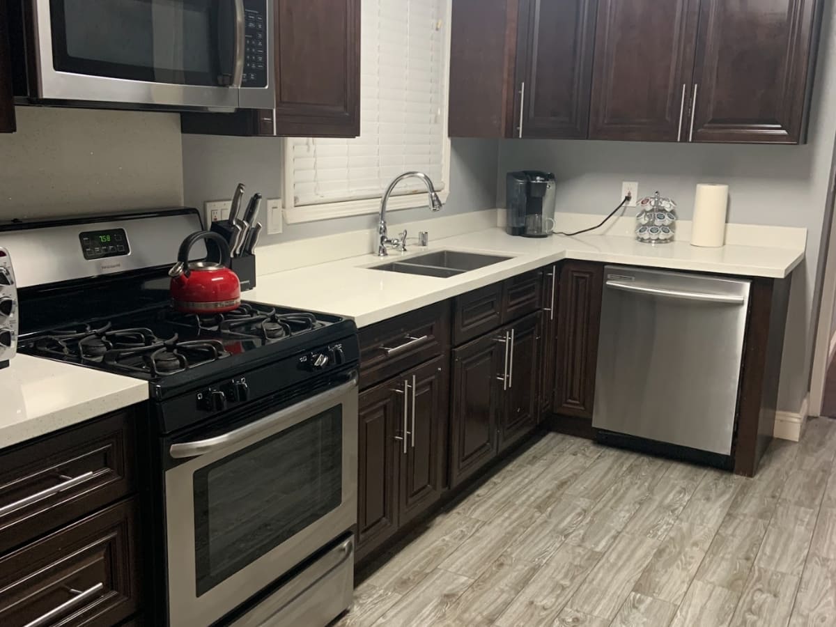 Spotless kitchen featuring dark wood cabinets, stainless steel appliances, and a clean countertop, demonstrating expert kitchen cleaning services in Concord.