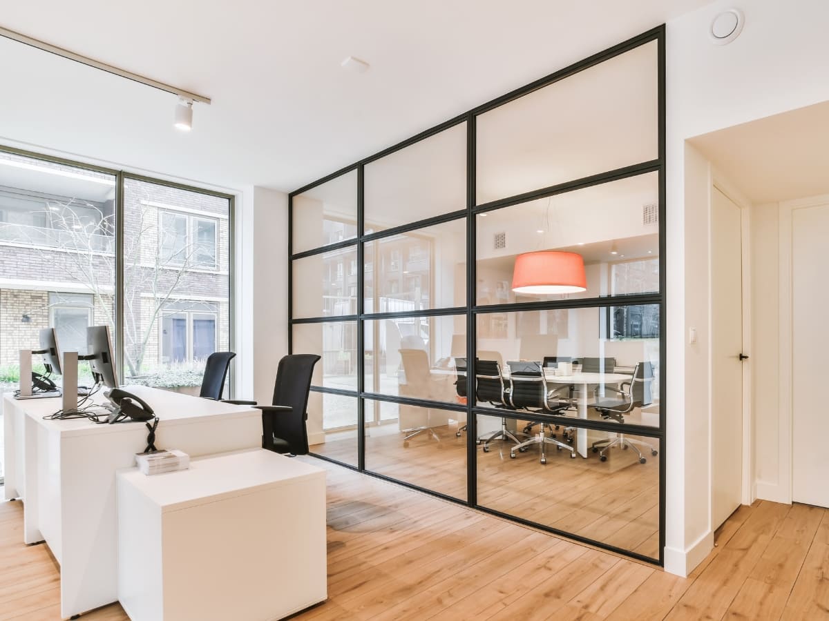 Modern office space with a glass-walled conference room and workstations, showcasing professional office cleaning services in Napa.