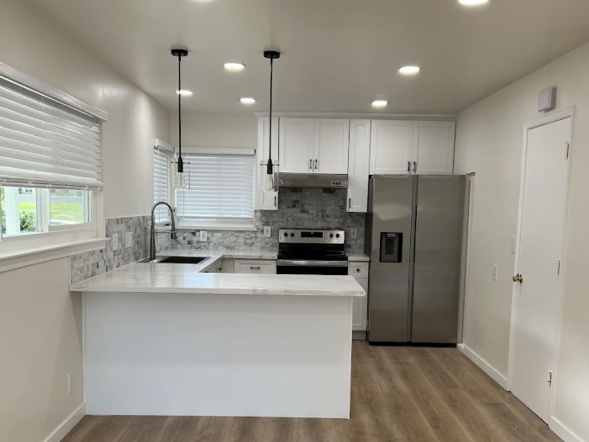 Clean, modern kitchen with white cabinetry, stainless steel appliances, and a marble countertop, representing high-quality Airbnb kitchen cleaning services in Concord