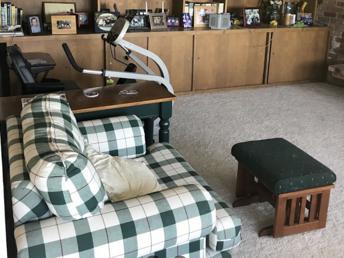 Living room with a plaid sofa, exercise equipment, and family photos on shelves, showcasing professional living room cleaning services in Napa.