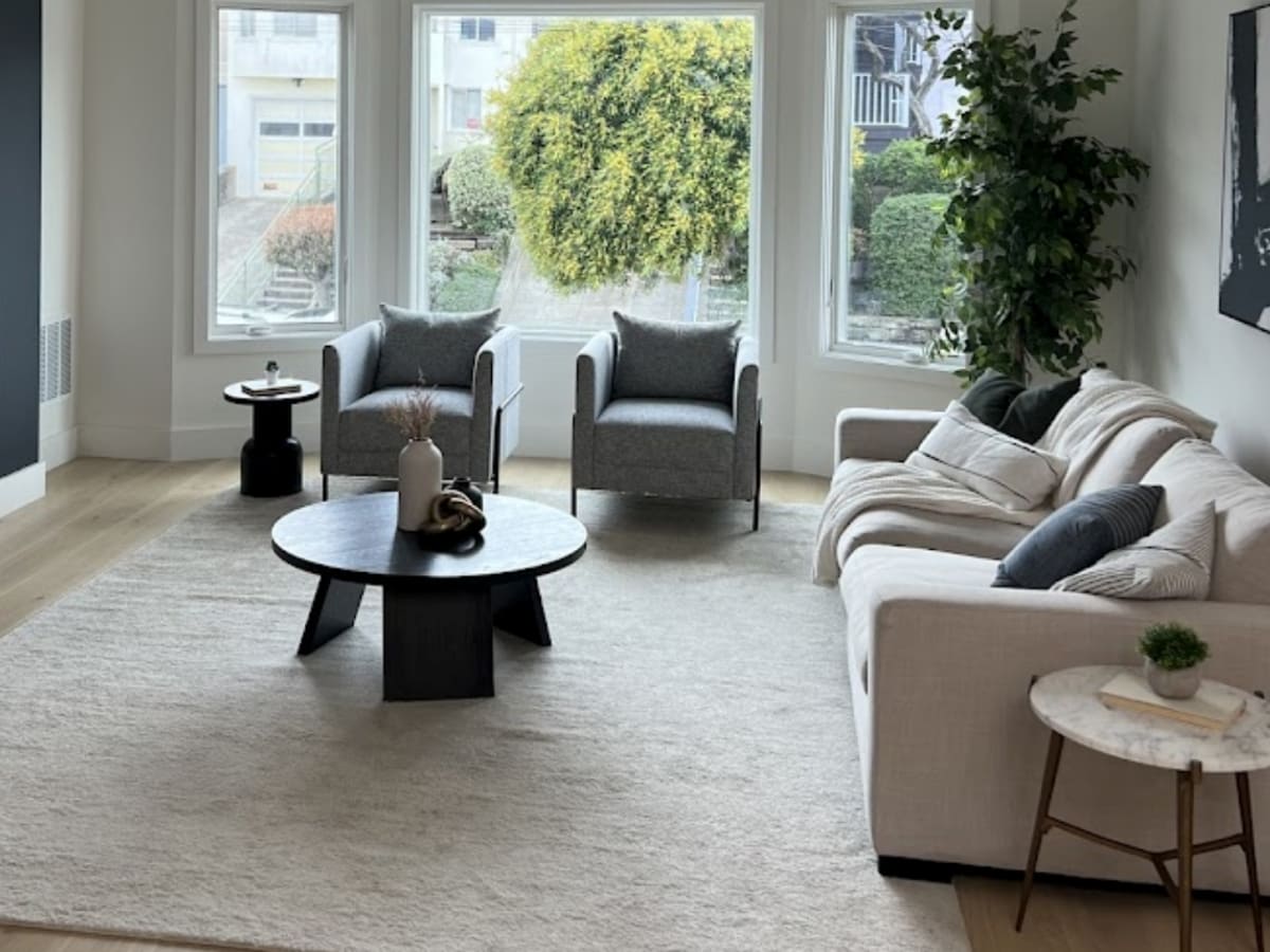 A well-organized home office with a large window, a green armchair, and wooden accents, providing an inspiring and productive workspace.