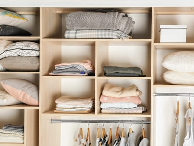 Neatly organized closet with folded linens and hanging clothes, emphasizing efficient storage and tidiness.