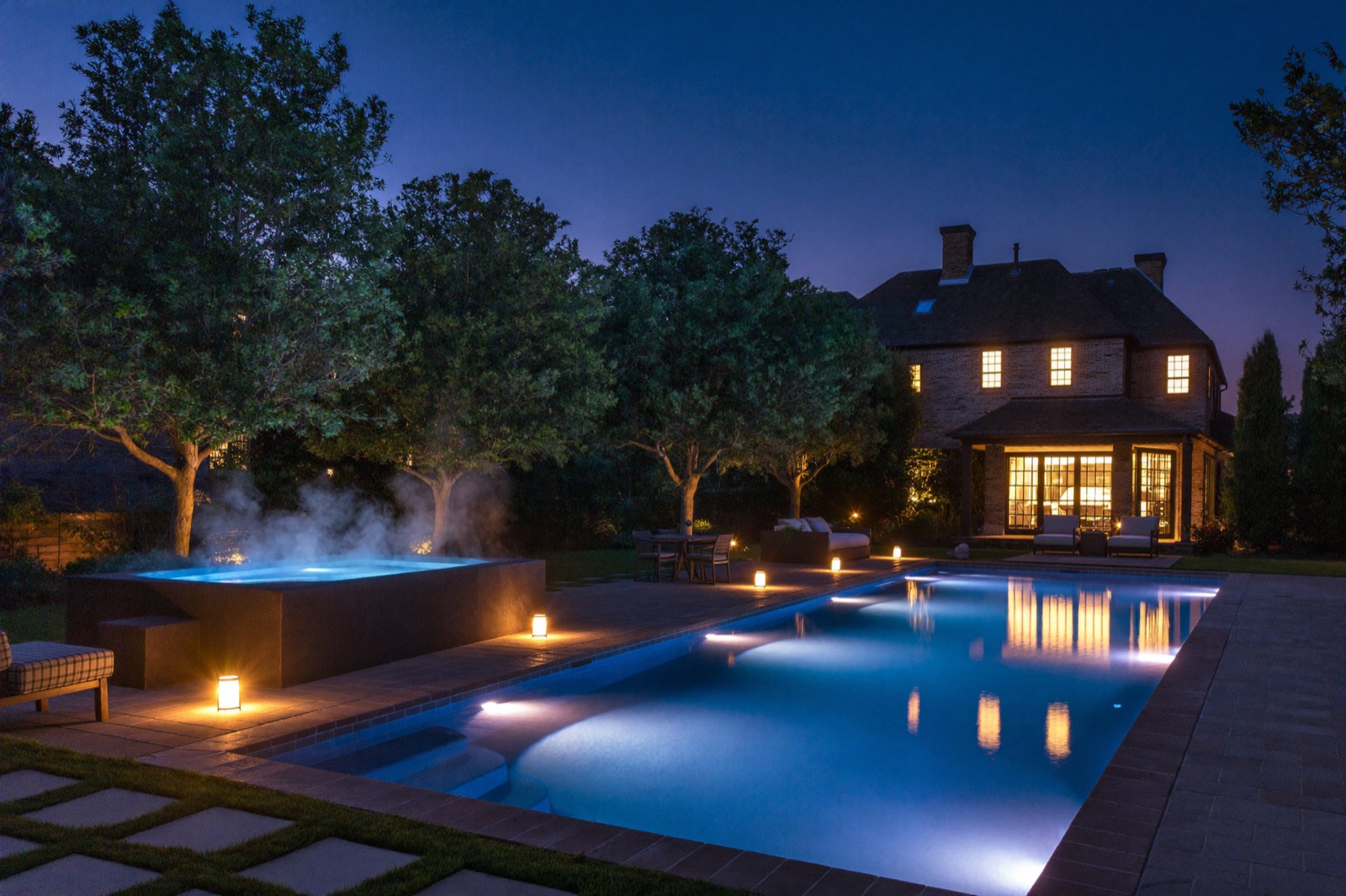 Pool and spa at dusk with underwater lighting and warm deck lighting