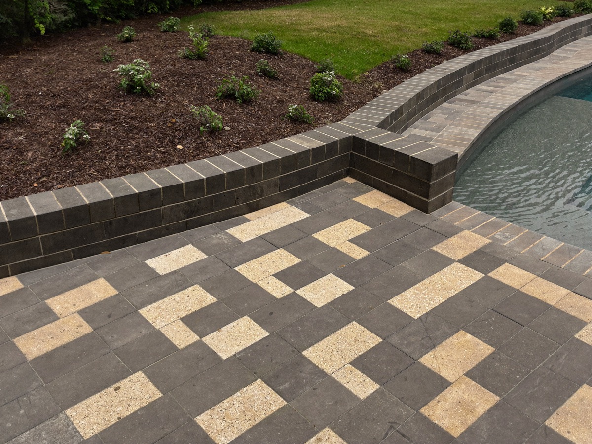 Paver patio and segmental block retaining wall bordering a lawn area