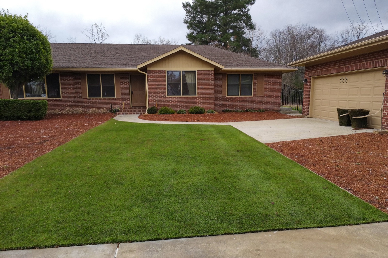 Artificial grass front lawn on a brick ranch home with a clean edge along the driveway
