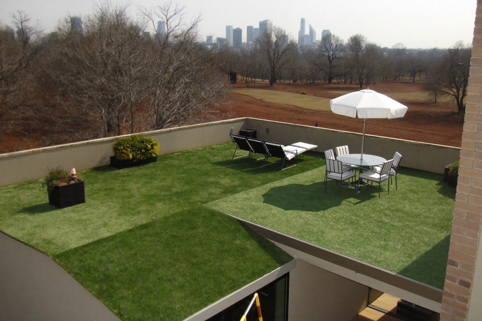 Rooftop terrace covered in artificial turf with outdoor furniture and planters