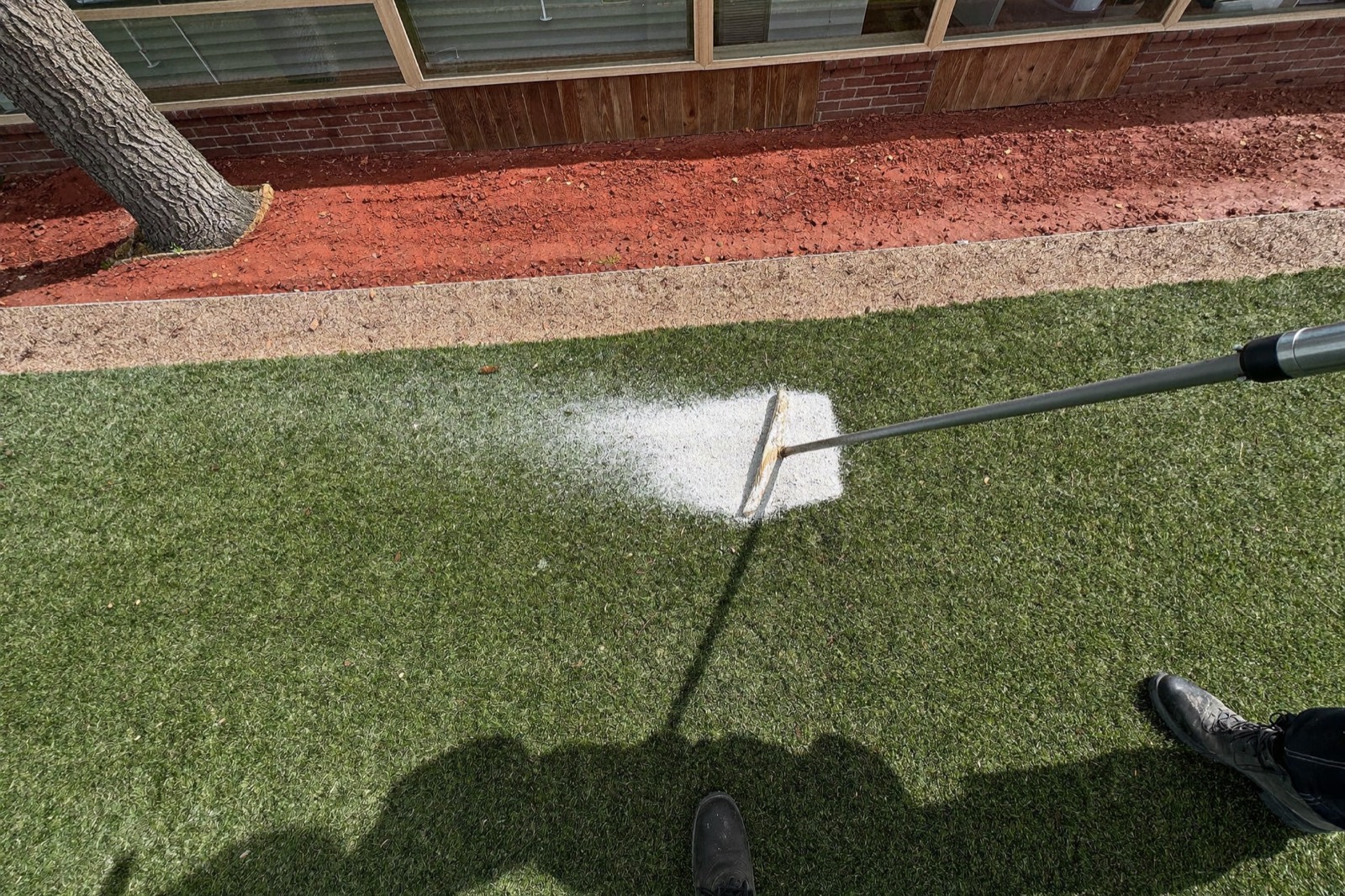 Power broom brushing silica sand infill down into the turf fibers