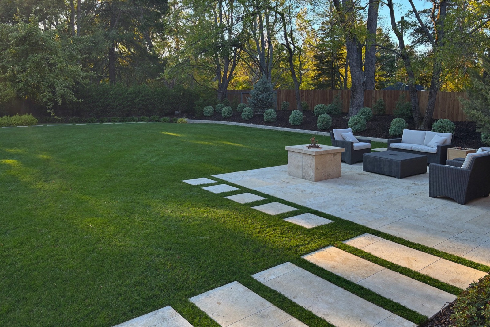 Artificial turf lawn with a travertine patio in a Lake Norman area backyard