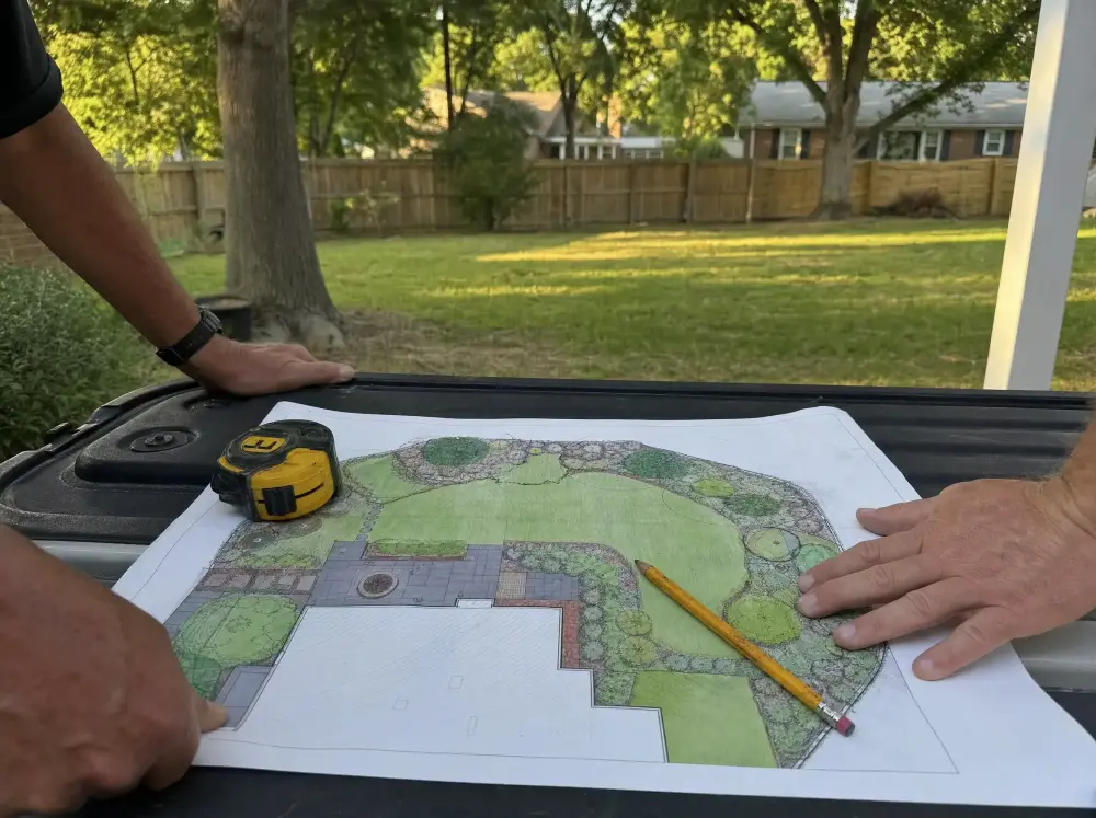 Illustration: a coloured back-yard plan laid flat on a tailgate with a pencil and tape measure, an ordinary lawn and wood fence behind it.