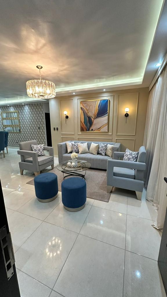 Bright living room with a gray sofa, blue ottomans, and a gold-framed painting