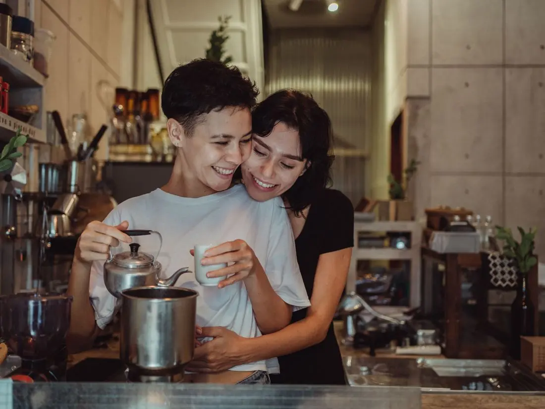 Two people laughing together in a kitchen.