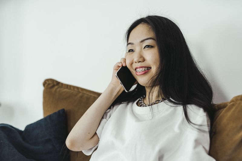 A woman smiling on a phone call at home.