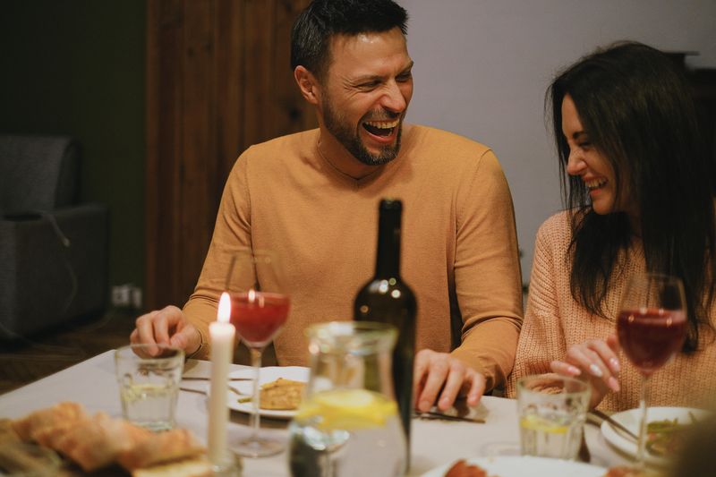 Two people laughing together over dinner.
