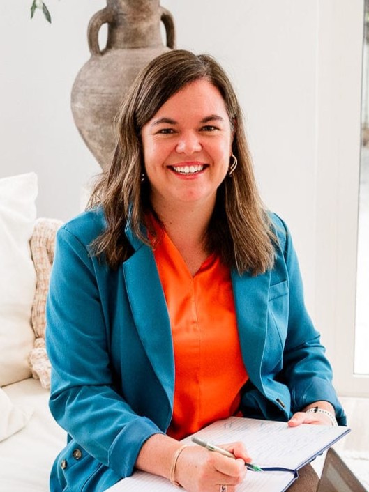 Di Van Der Walt, speech pathologist, smiling with a notebook