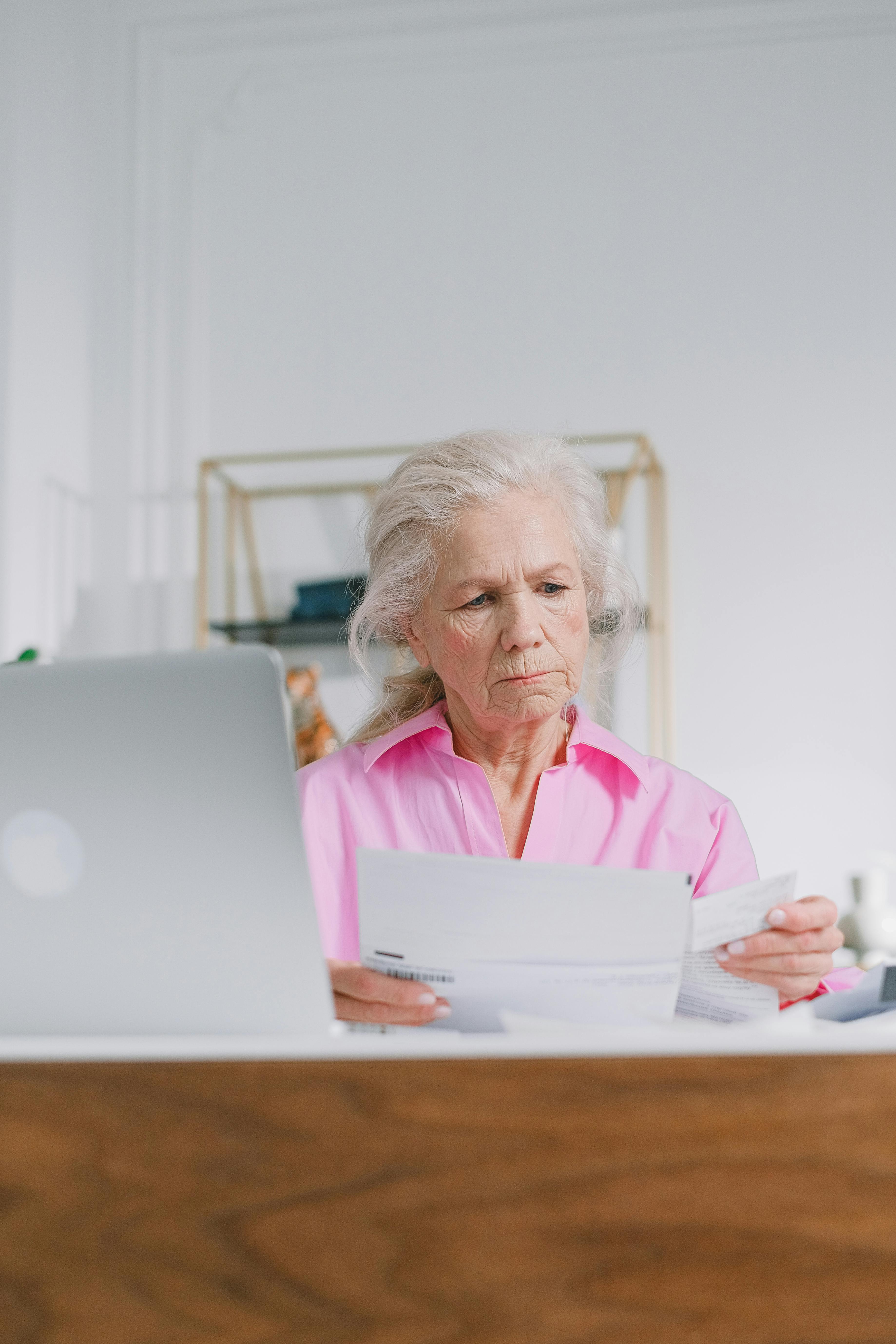 Senior woman reviewing her long-term care insurance policy at her home desk