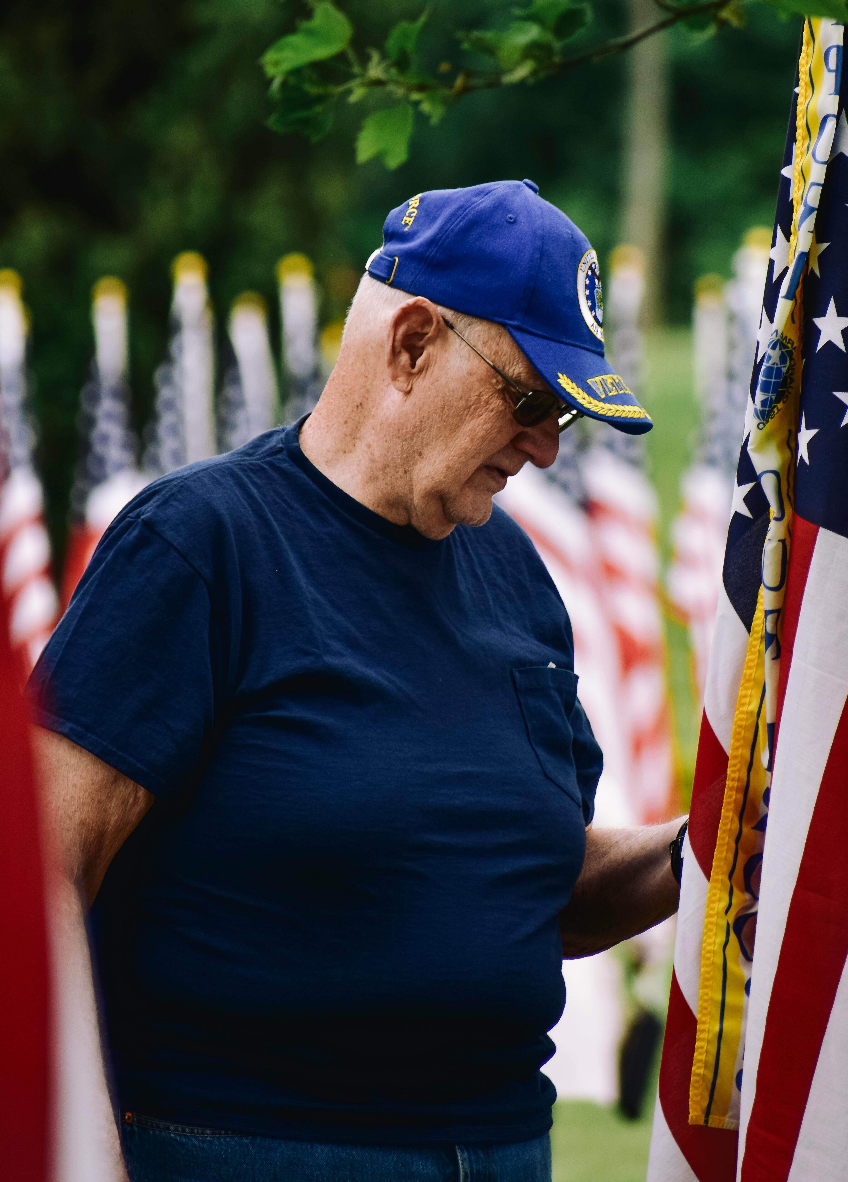 Senior U.S. veteran standing beside American flags, representing VA long-term care benefits