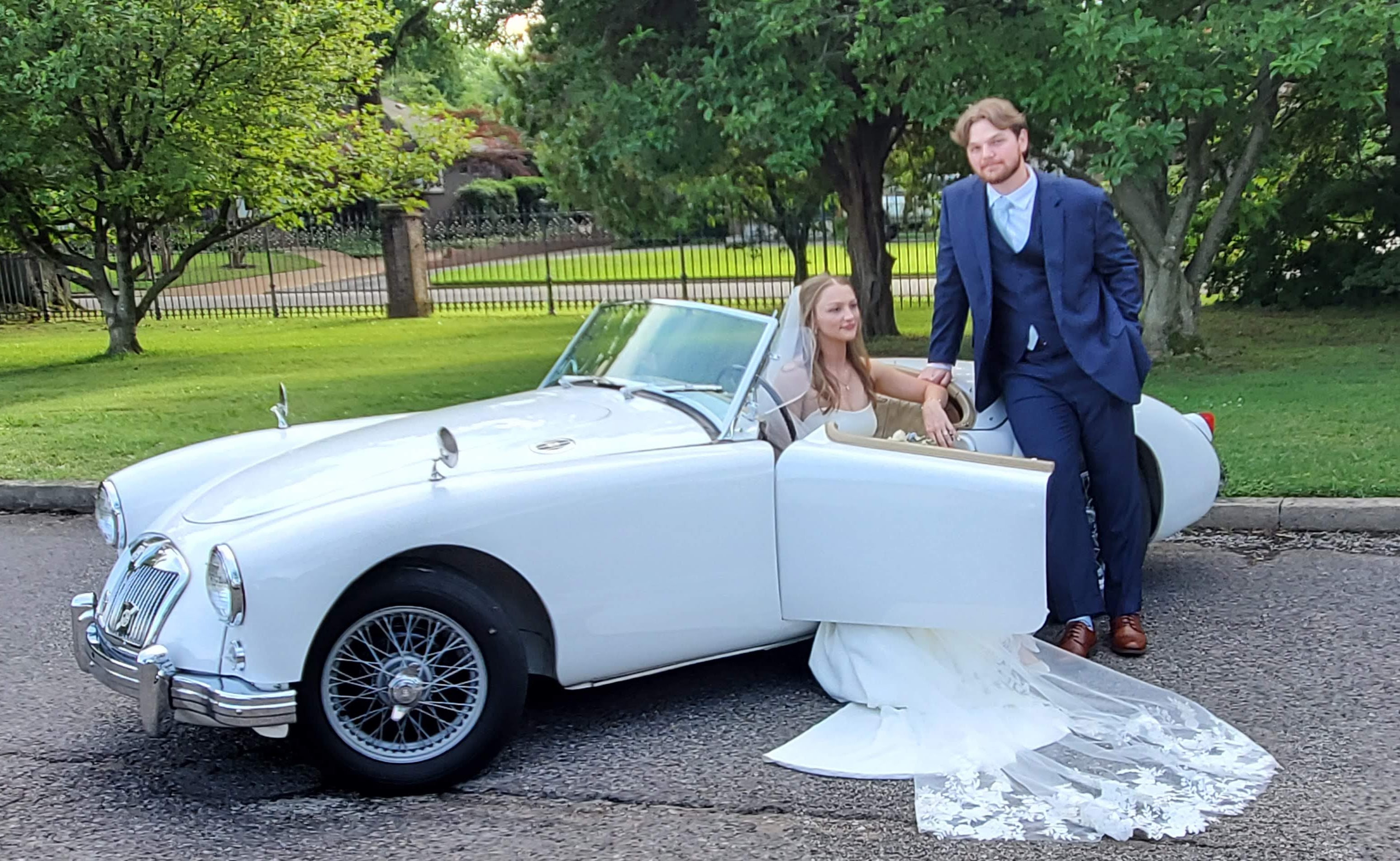 Bride and groom with the Getaway Car, looking to camera