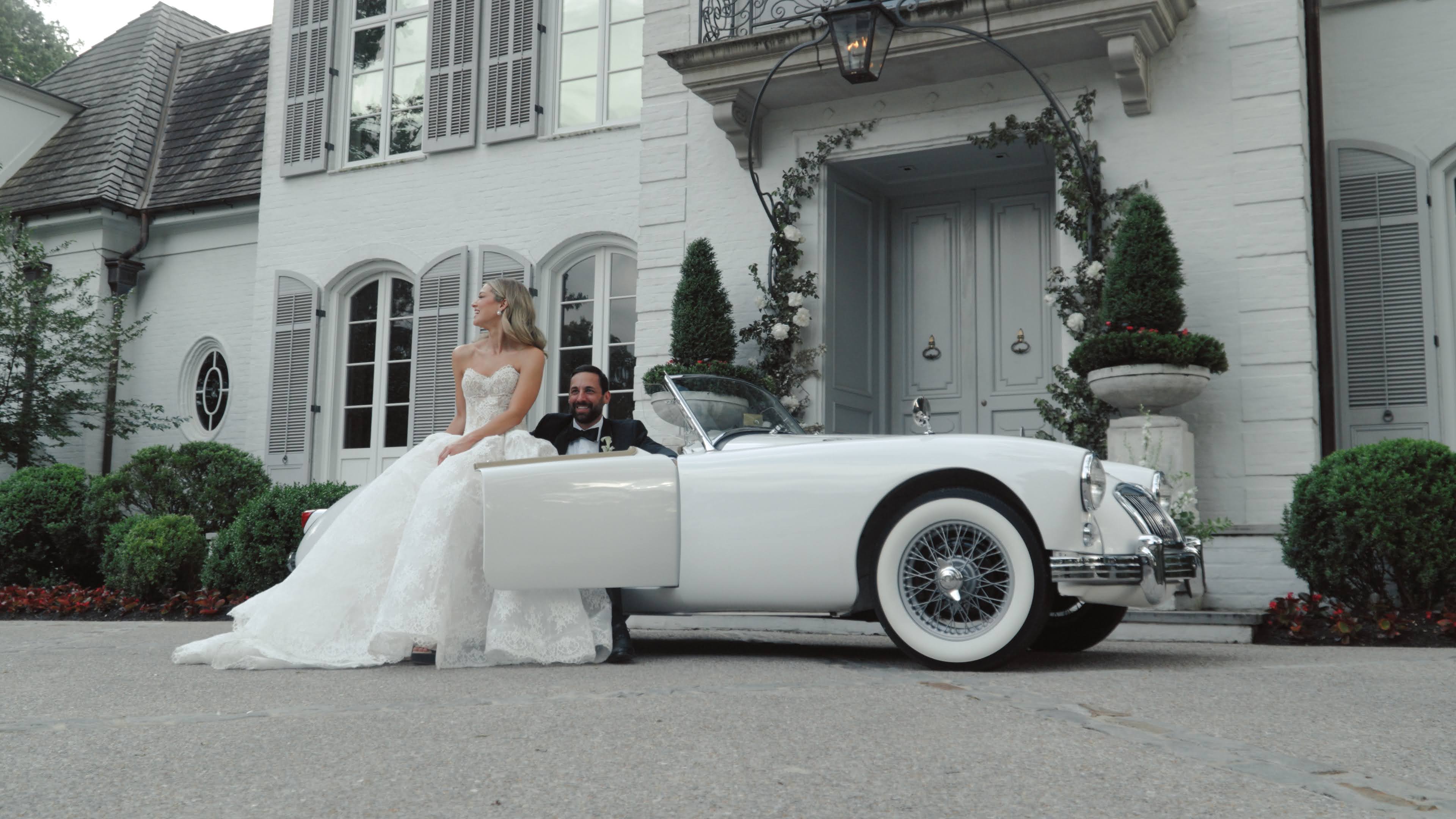 Newlywed couple seated in the Getaway Car at a grand estate